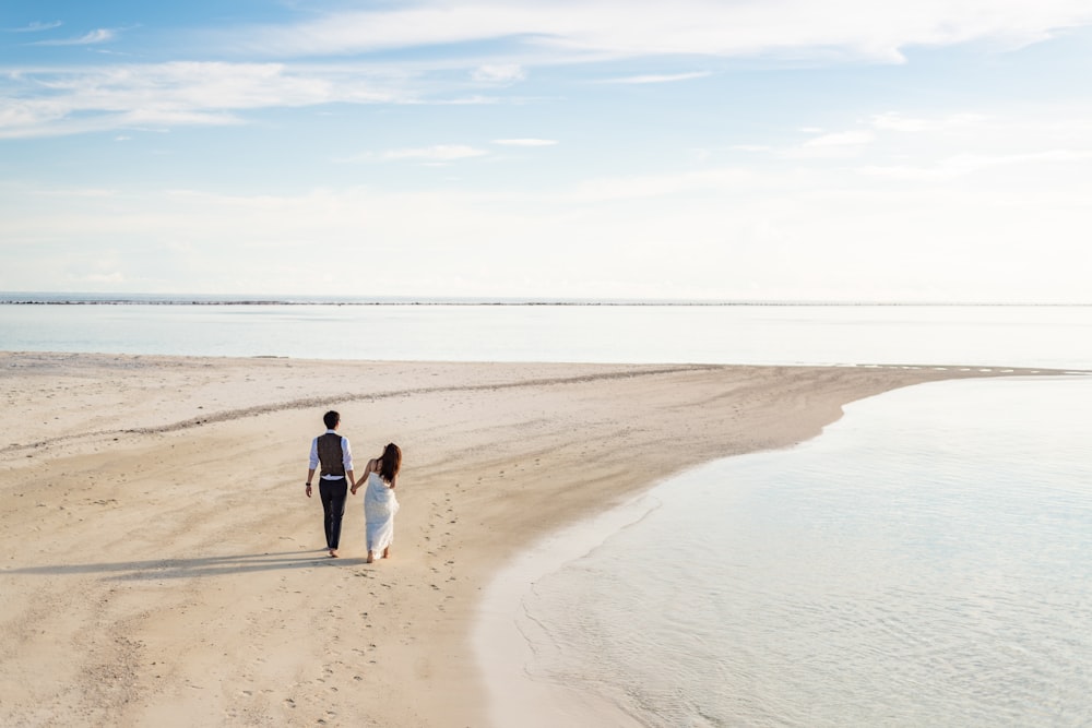 2 mujeres y hombre caminando en la playa durante el día