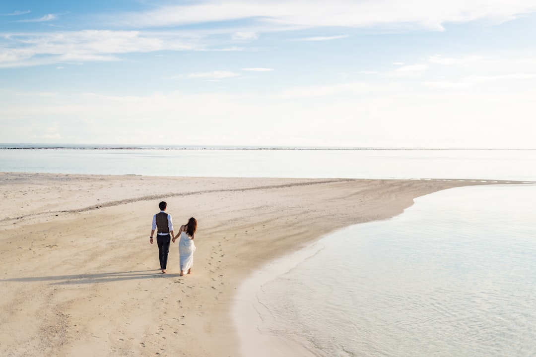 2 women and man walking on beach during daytime