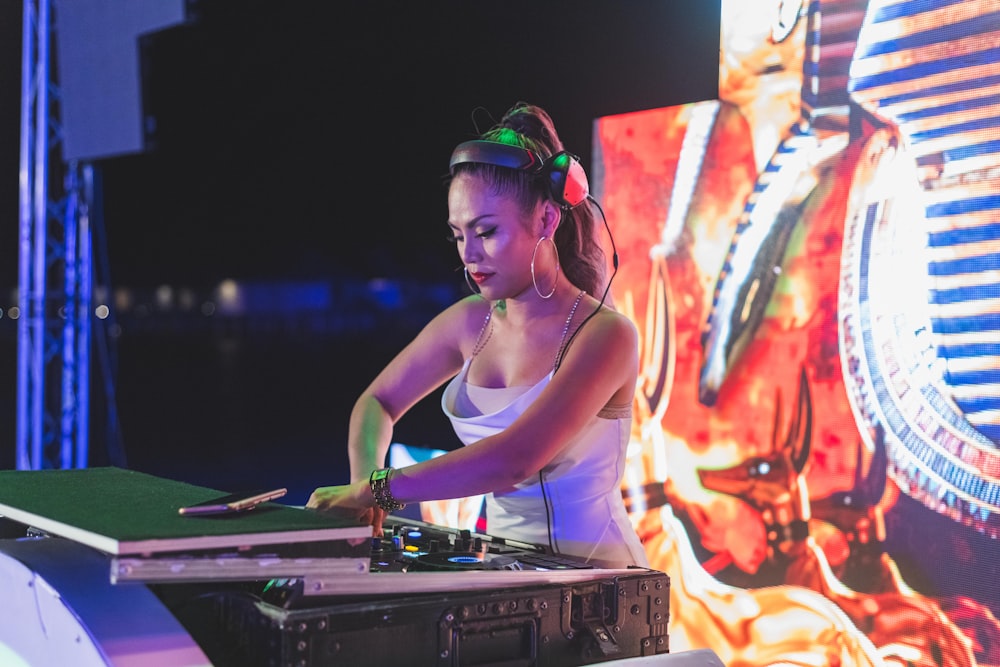 woman in green tank top wearing green headphones playing dj controller