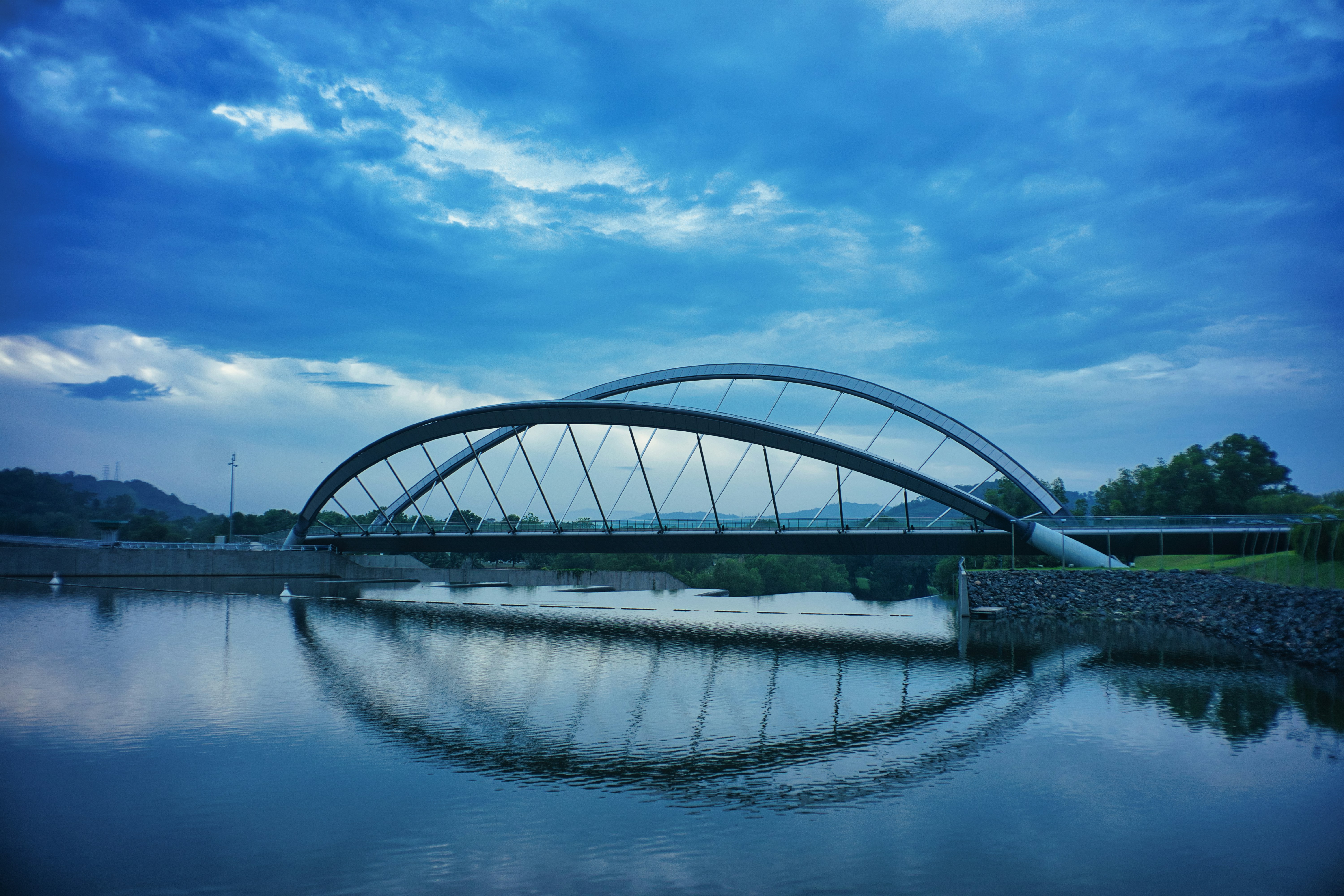 gray metal bridge over river under blue sky during daytime
