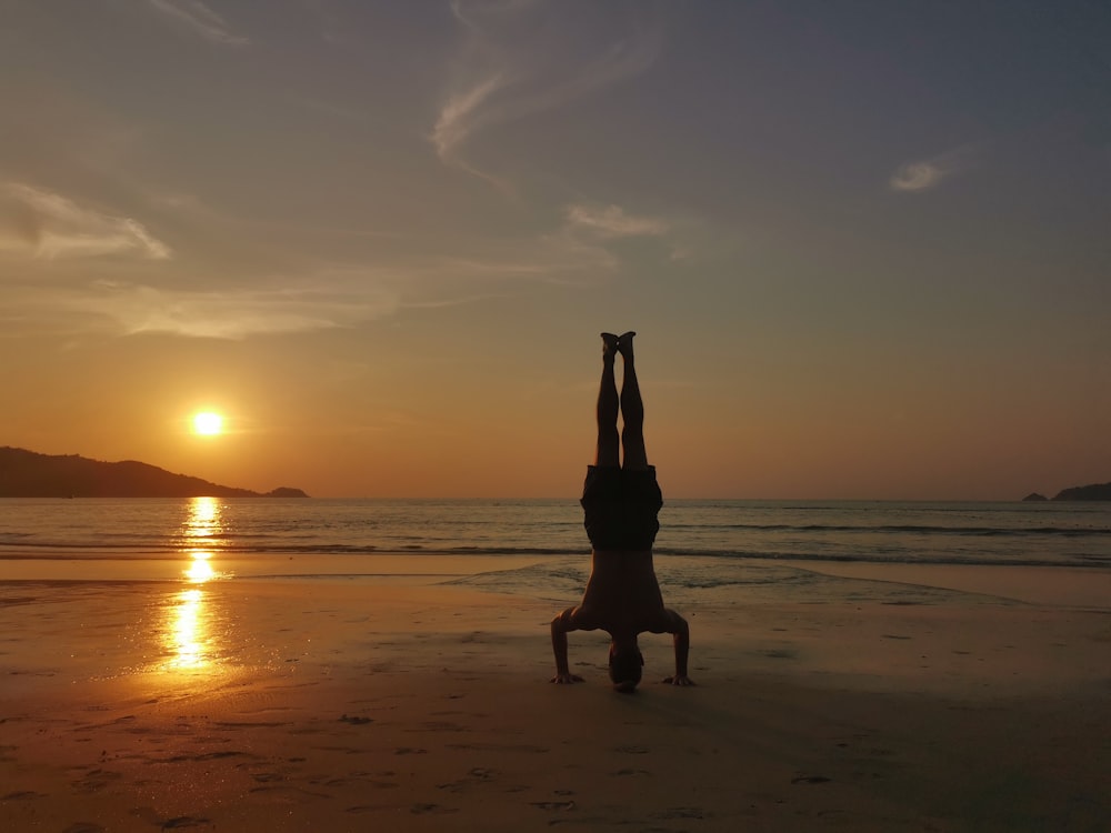 silhouette of woman standing on beach during sunset