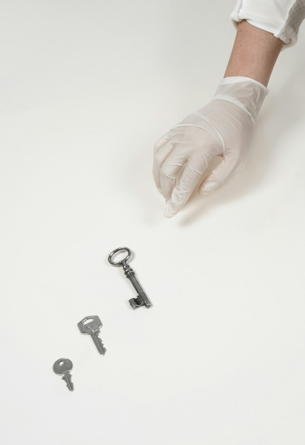 person holding white gloves with silver skeleton key
