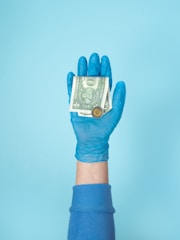person in blue gloves holding 1 us dollar bill