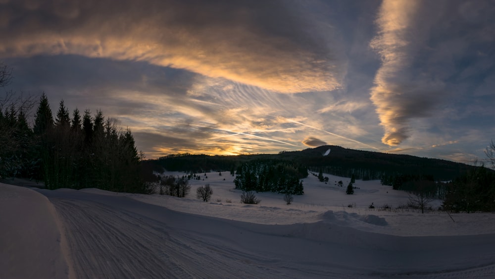 snow covered field under cloudy sky during daytime