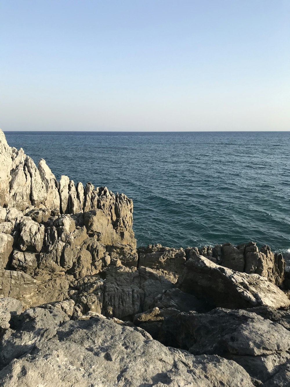 昼間の青い海のそばの灰色の岩山