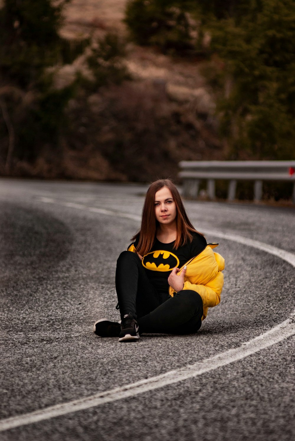 woman in yellow long sleeve shirt and black pants sitting on road during daytime