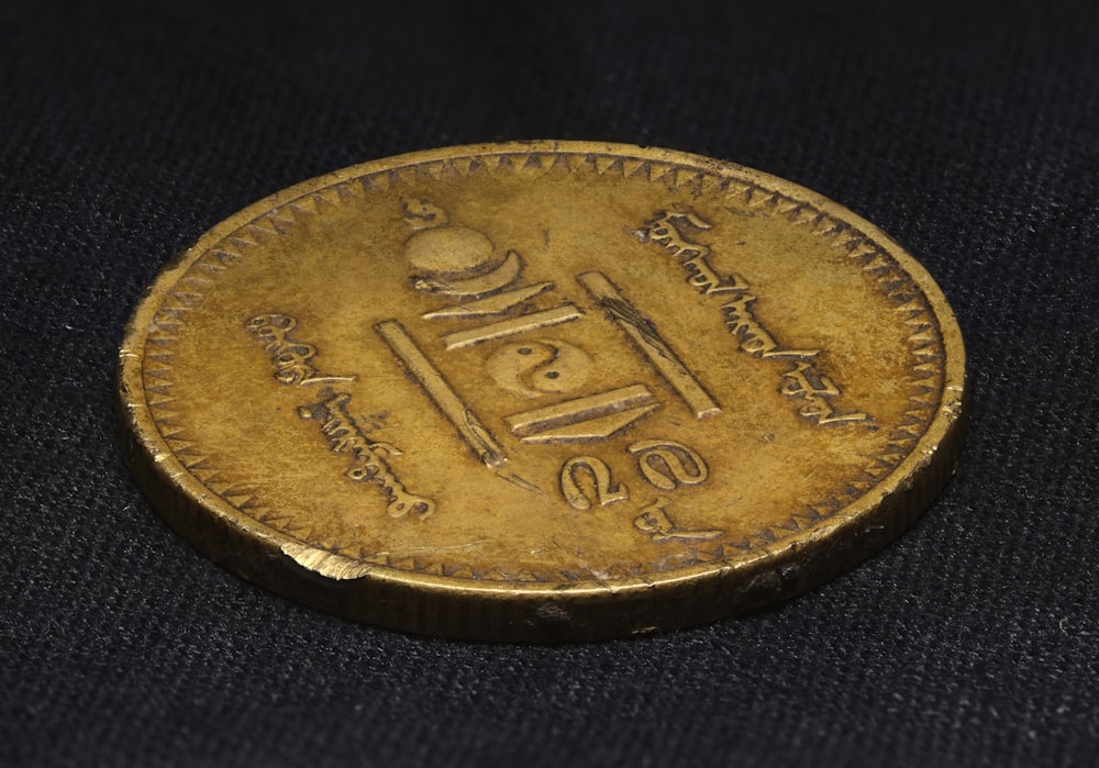 gold round coin on black textile