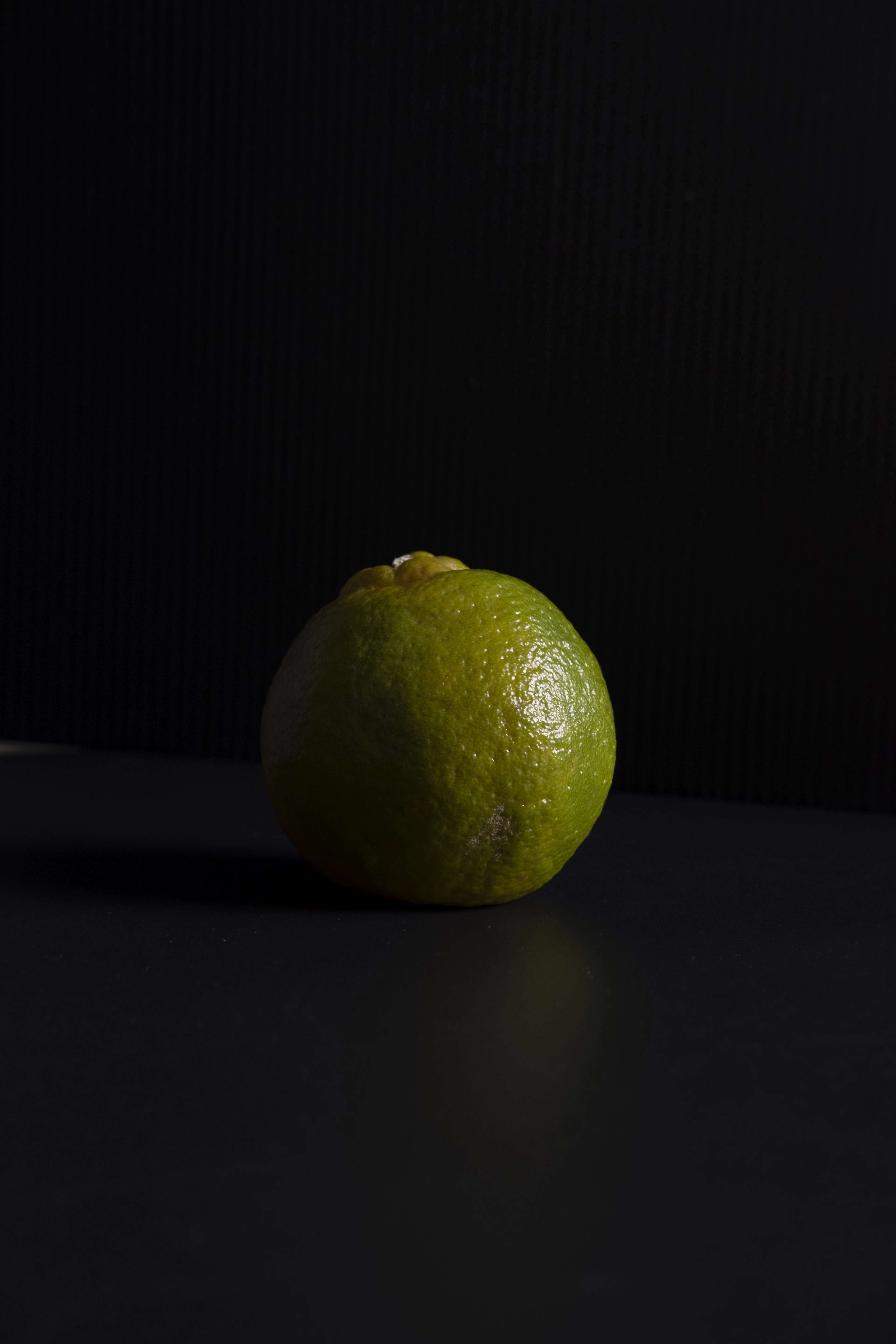 A single bergamot on a dark surface