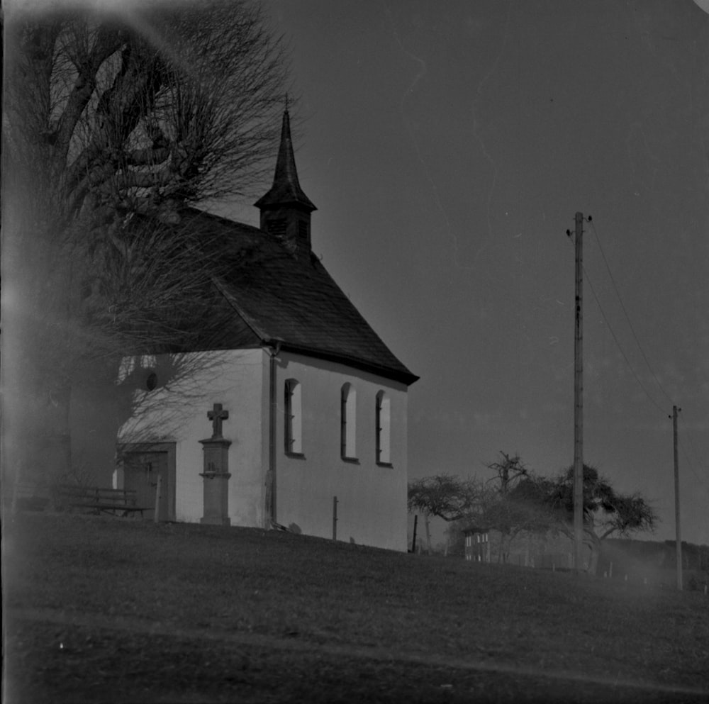 grayscale photo of church near bare trees