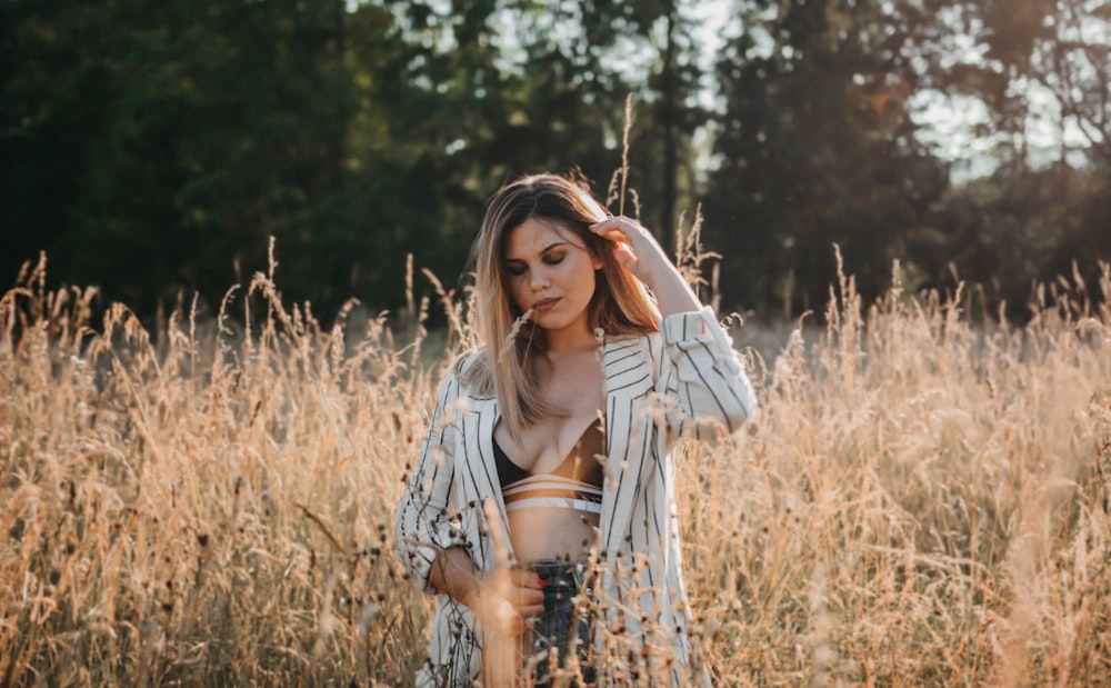 woman in white and black long sleeve shirt standing on brown grass field during daytime