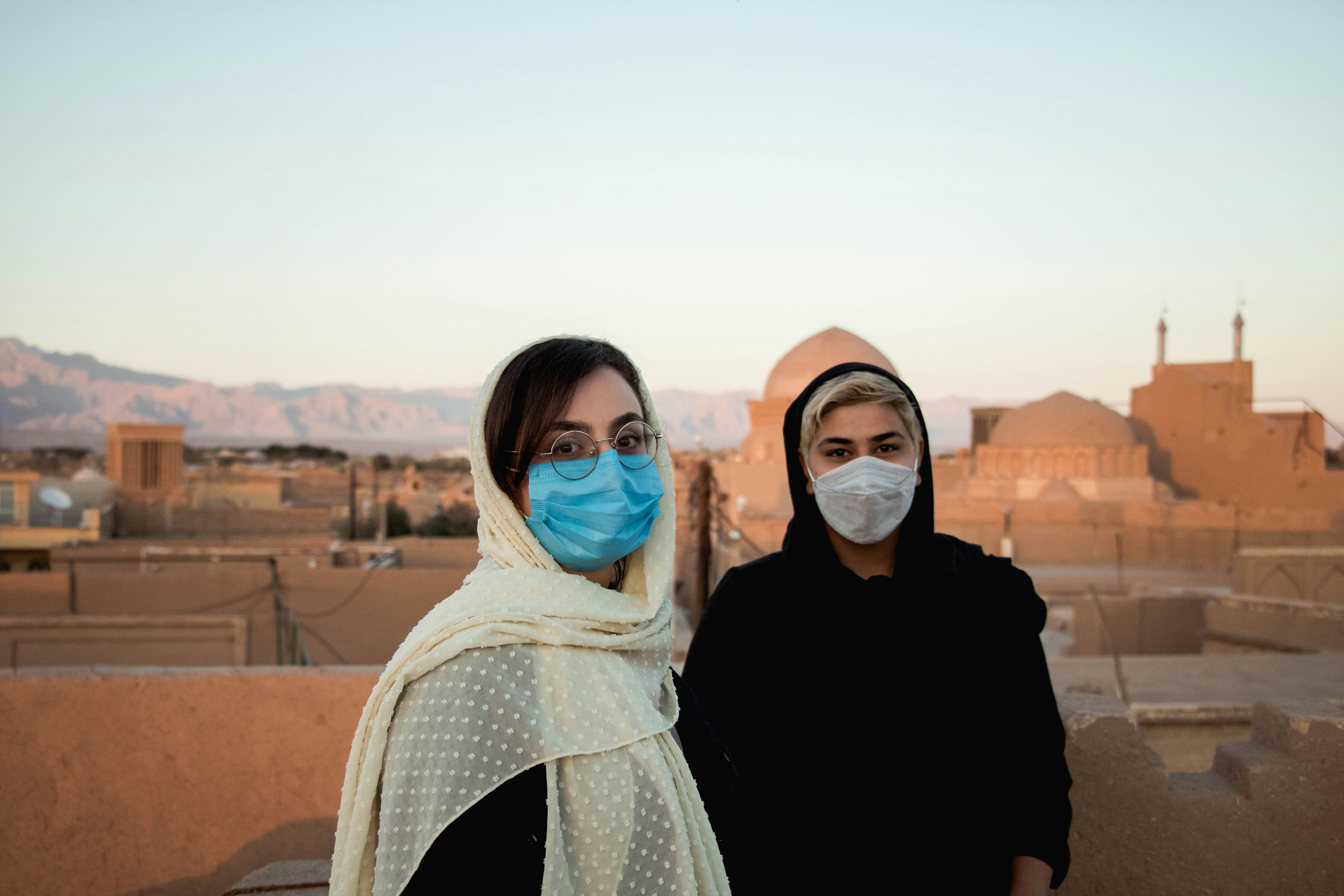 woman in white hijab standing beside woman in black shirt