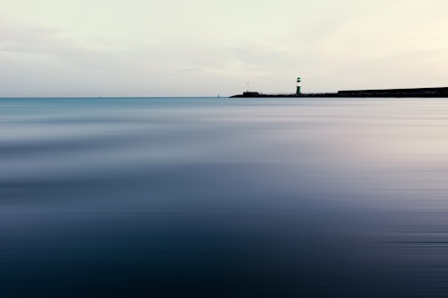 A serene lighthouse guiding through a foggy sea.