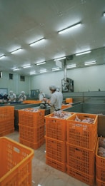 man in white dress shirt standing near orange plastic crate