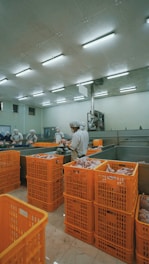 man in white dress shirt standing near orange plastic crate