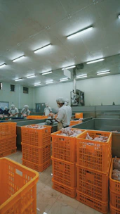 man in white dress shirt standing near orange plastic crate
