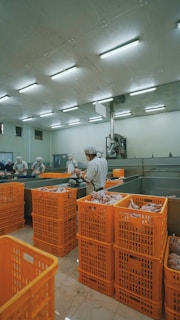 man in white dress shirt standing near orange plastic crate