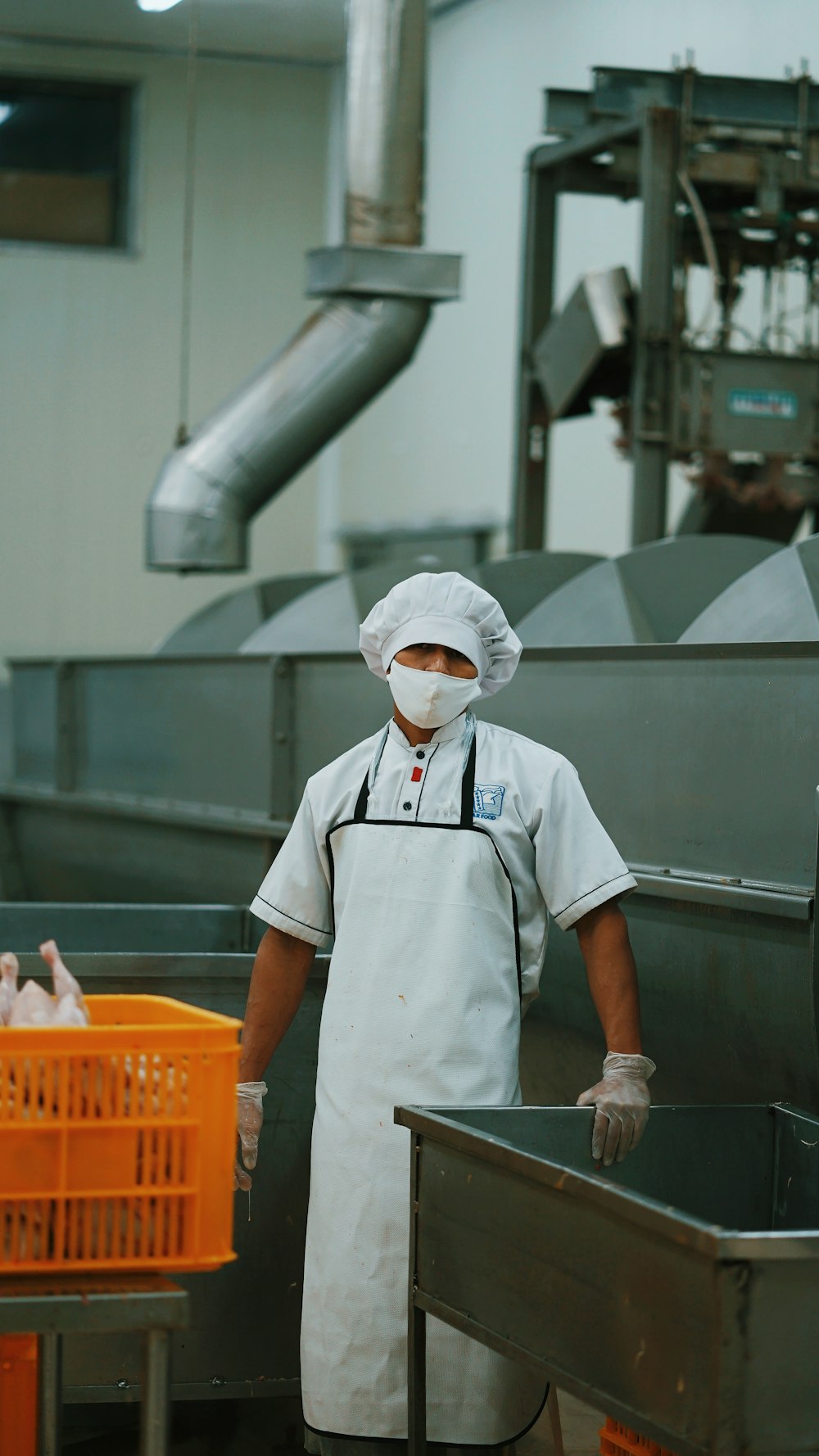 Hombre con uniforme de chef blanco sosteniendo un tubo de metal gris