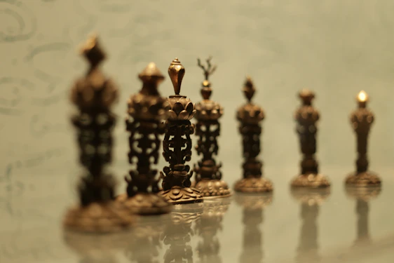 Elegant classical Roman-inspired chess pieces arranged on a marble table with the Colosseum softly blurred in the background.