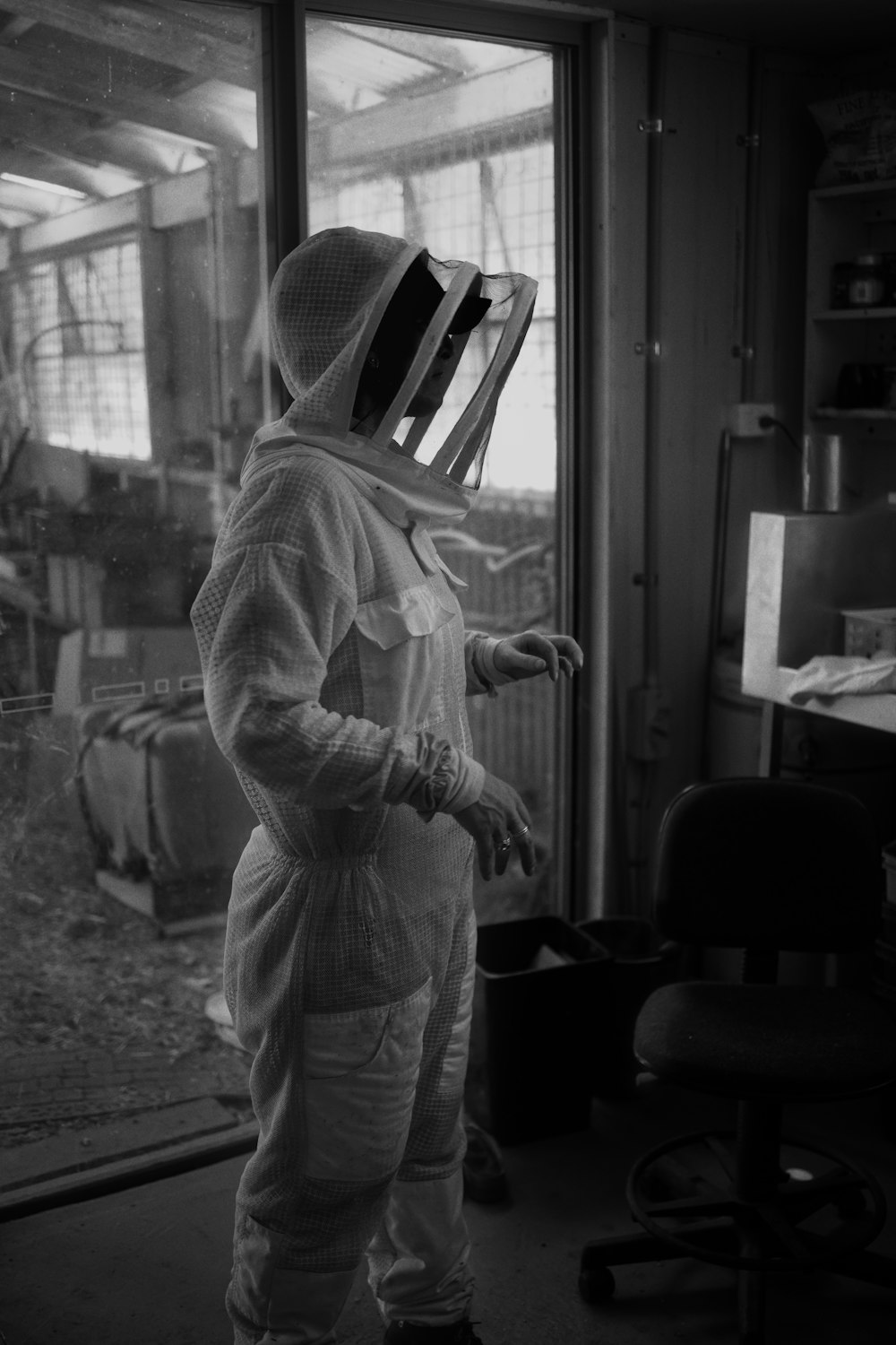 man in white dress shirt and white hat standing near window