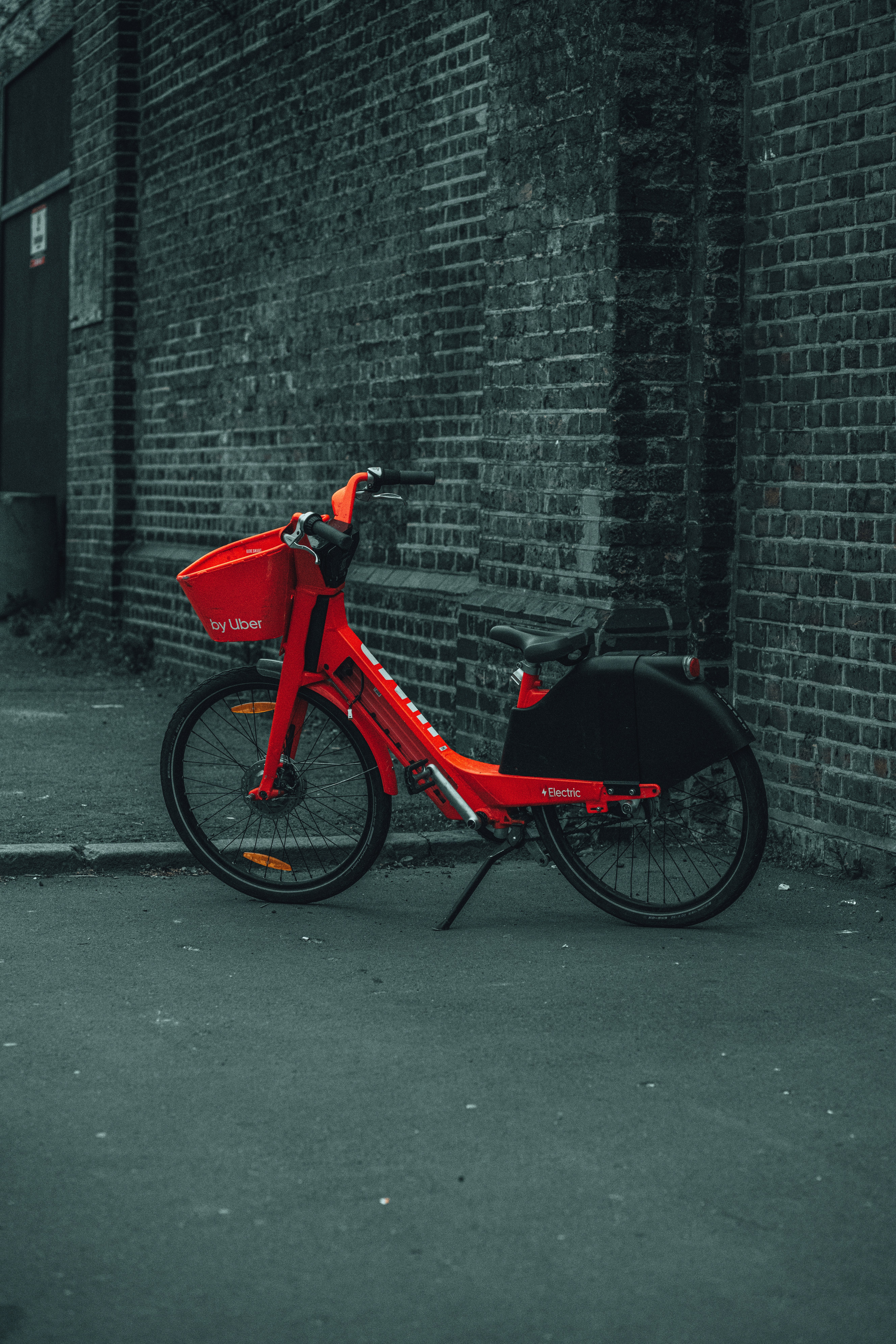 red and black bicycle parked beside gray brick wall