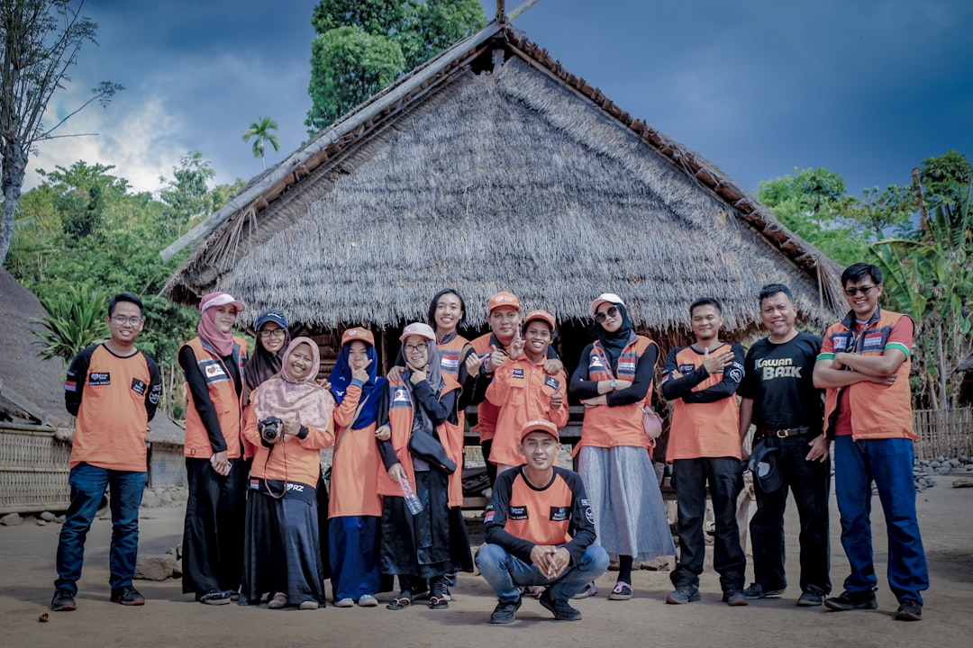 group of people standing near brown wooden house,