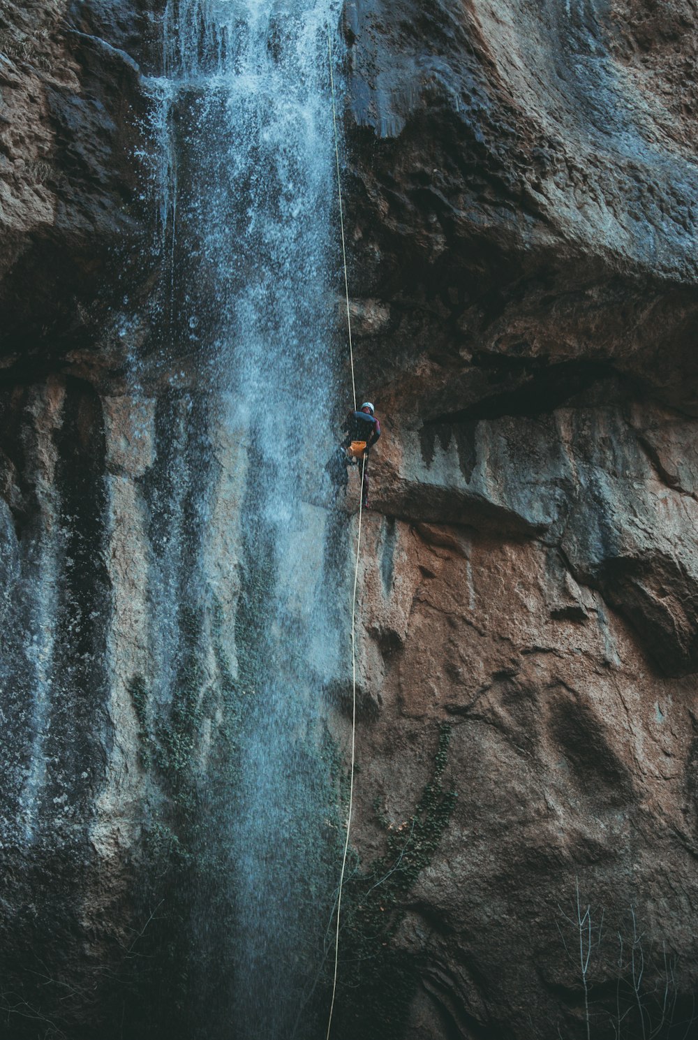 Persona in giacca blu che si arrampica sulla montagna rocciosa durante il giorno