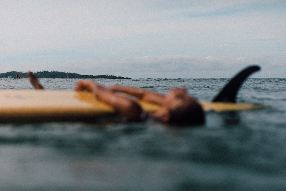 person lying on brown sand on body of water during daytime