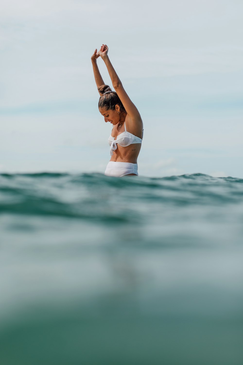 woman in white bikini lying on water during daytime