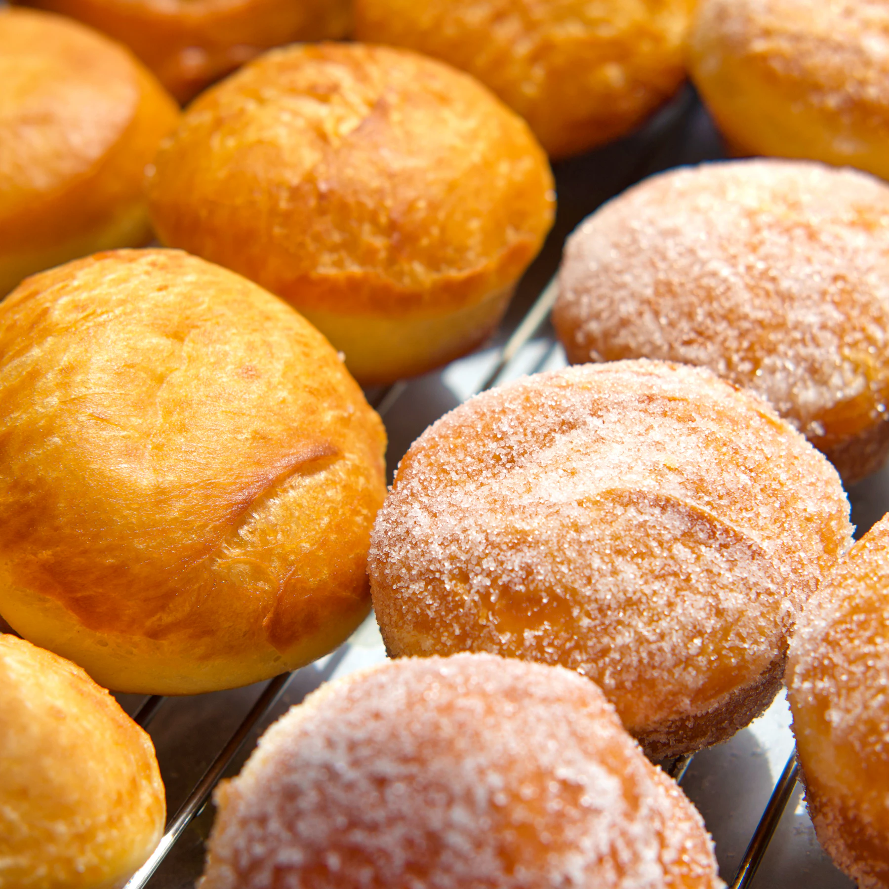 Plain and sugar-rolled round donuts cooling on a wire rack
