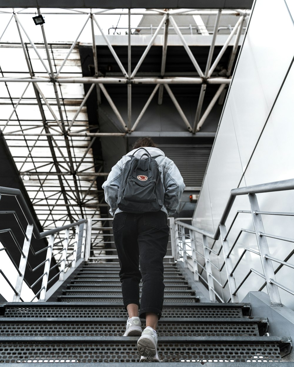 man in blue jacket and black pants walking on black staircase