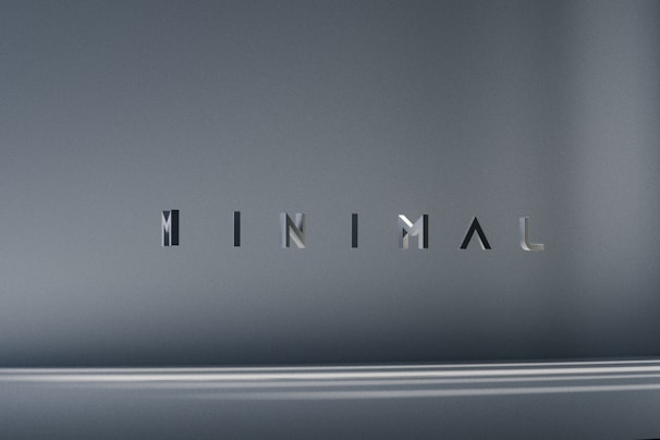 The image consists of the word 'MINIMAL' in a modern, sleek font. The background is a smooth gradient of gray shades, which emphasizes the simplicity and elegance of the design.