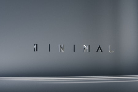 The image consists of the word 'MINIMAL' in a modern, sleek font. The background is a smooth gradient of gray shades, which emphasizes the simplicity and elegance of the design.