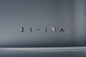 The image consists of the word 'MINIMAL' in a modern, sleek font. The background is a smooth gradient of gray shades, which emphasizes the simplicity and elegance of the design.
