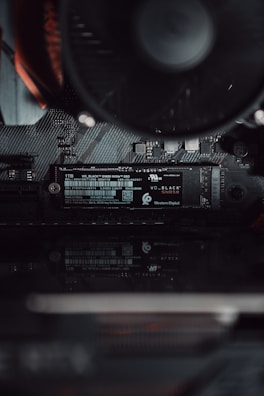 A close-up view of a computer's internal hardware focusing on a Western Digital NVMe solid-state drive installed on a motherboard. The components are sleek, showcasing fine electronic circuits and a smooth black finish.