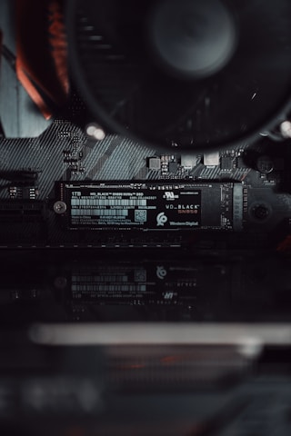 A close-up view of a computer's internal hardware focusing on a Western Digital NVMe solid-state drive installed on a motherboard. The components are sleek, showcasing fine electronic circuits and a smooth black finish.