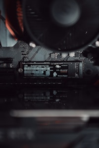 A close-up view of a computer's internal hardware focusing on a Western Digital NVMe solid-state drive installed on a motherboard. The components are sleek, showcasing fine electronic circuits and a smooth black finish.