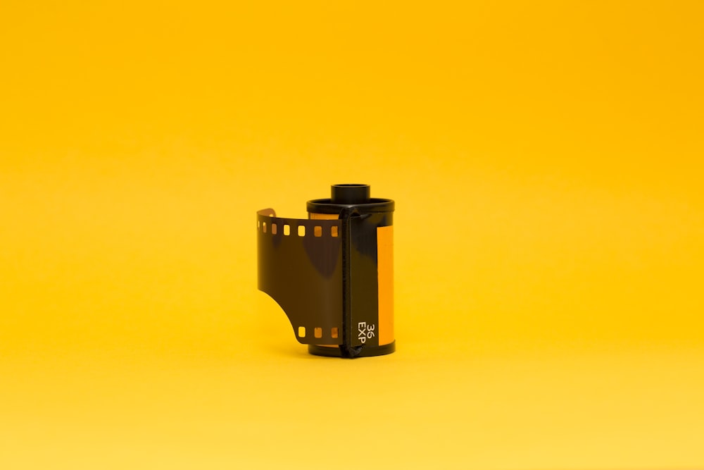 Fotocamera nera su superficie gialla