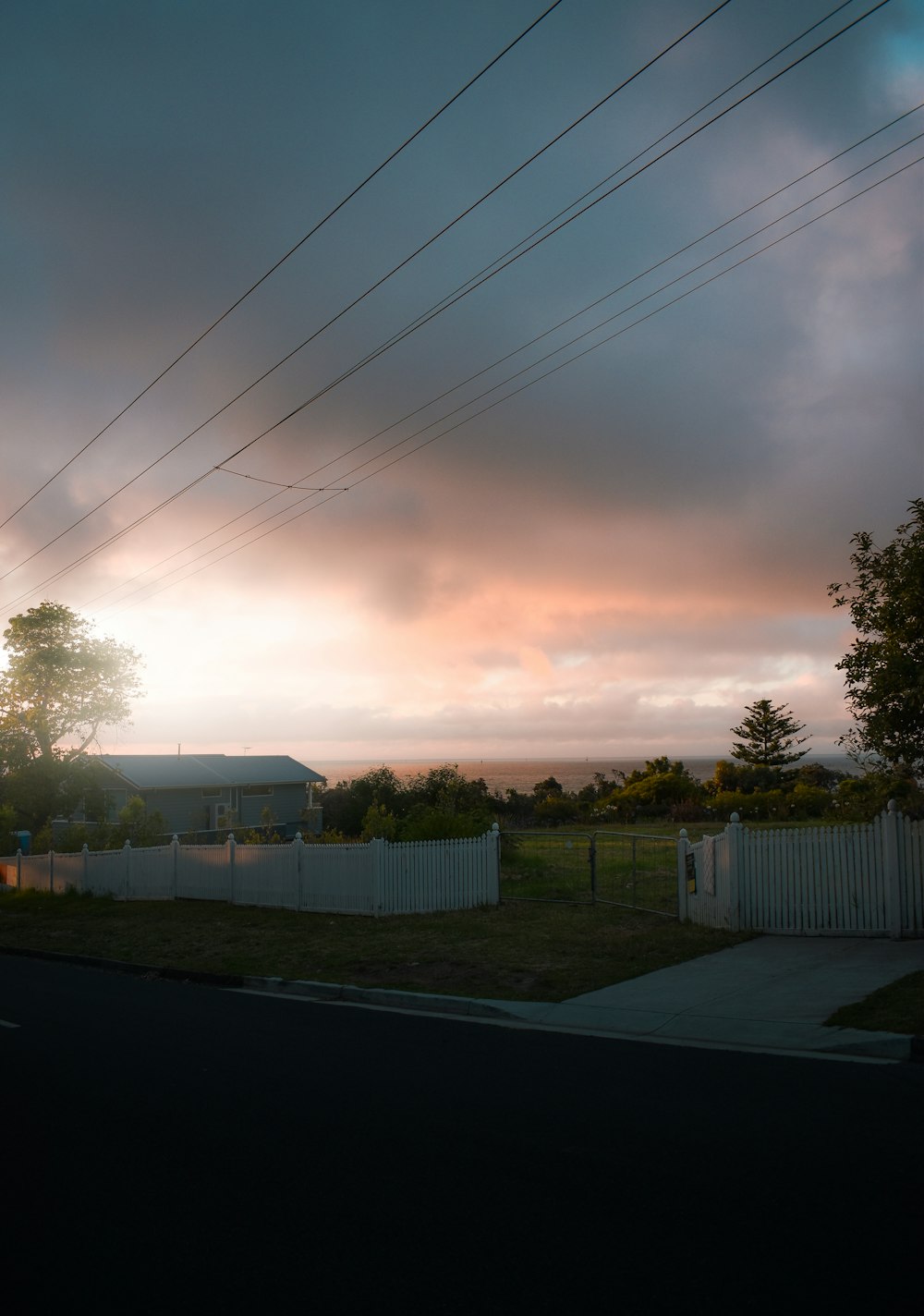 white wooden fence near green trees under white clouds during daytime