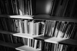 Photography of a bookshelf filled with Marco di Caprio’s books, softly lit in a warm study.