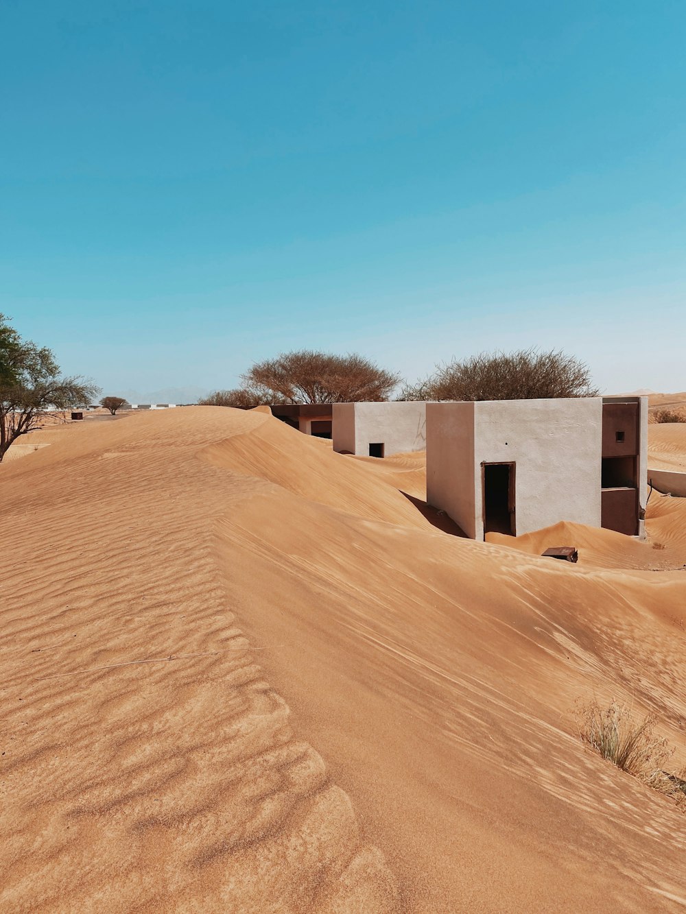 낮에는 푸른 하늘 아래 갈색 모래 위에 있는 흰색과 갈색 콘크리트 집