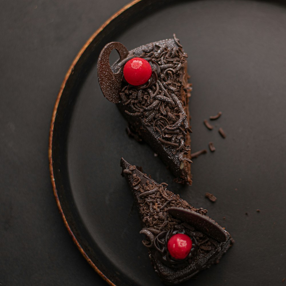 chocolate cake with red and gold baubles on black round plate