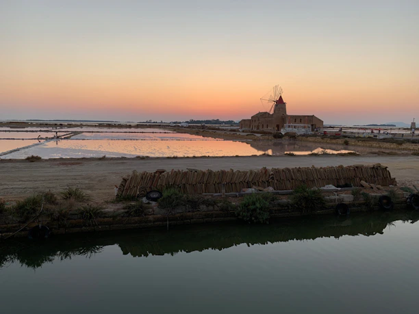 A vibrant sunset over the vast salt flats with travelers exploring the landscape.