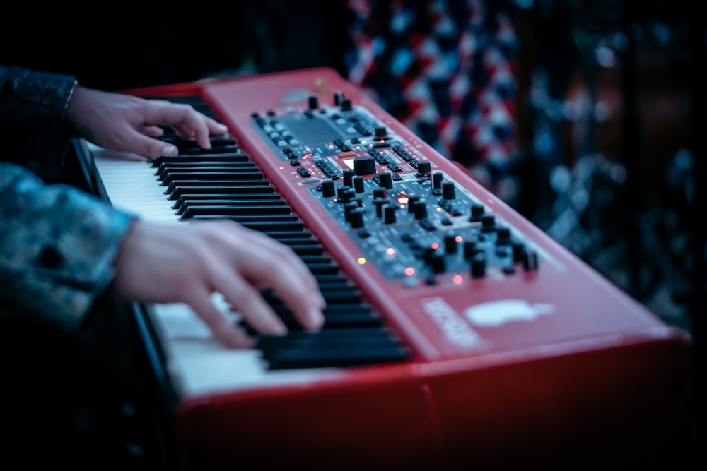 persona tocando el piano rojo y blanco