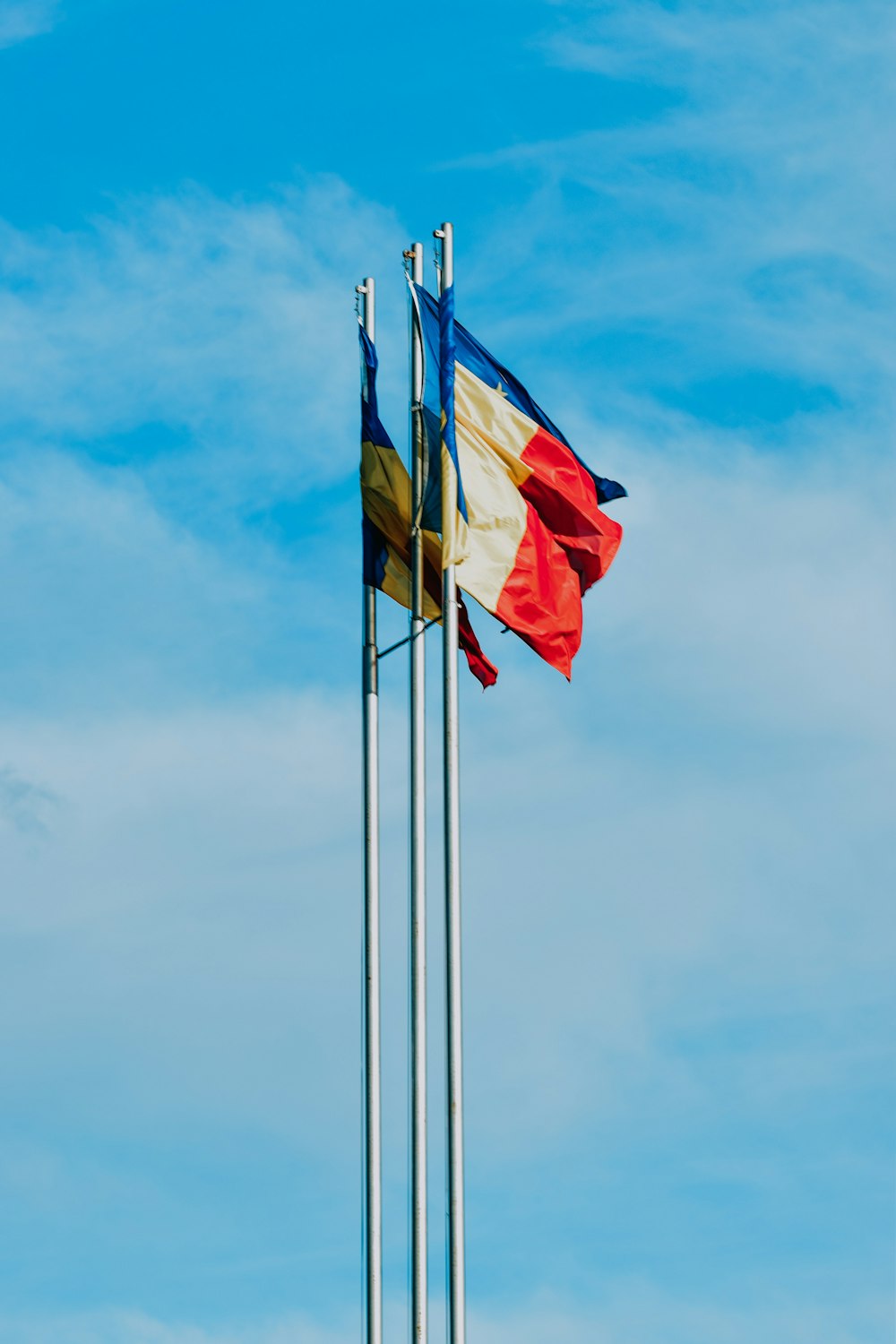 yellow red and blue flag under white clouds and blue sky during daytime