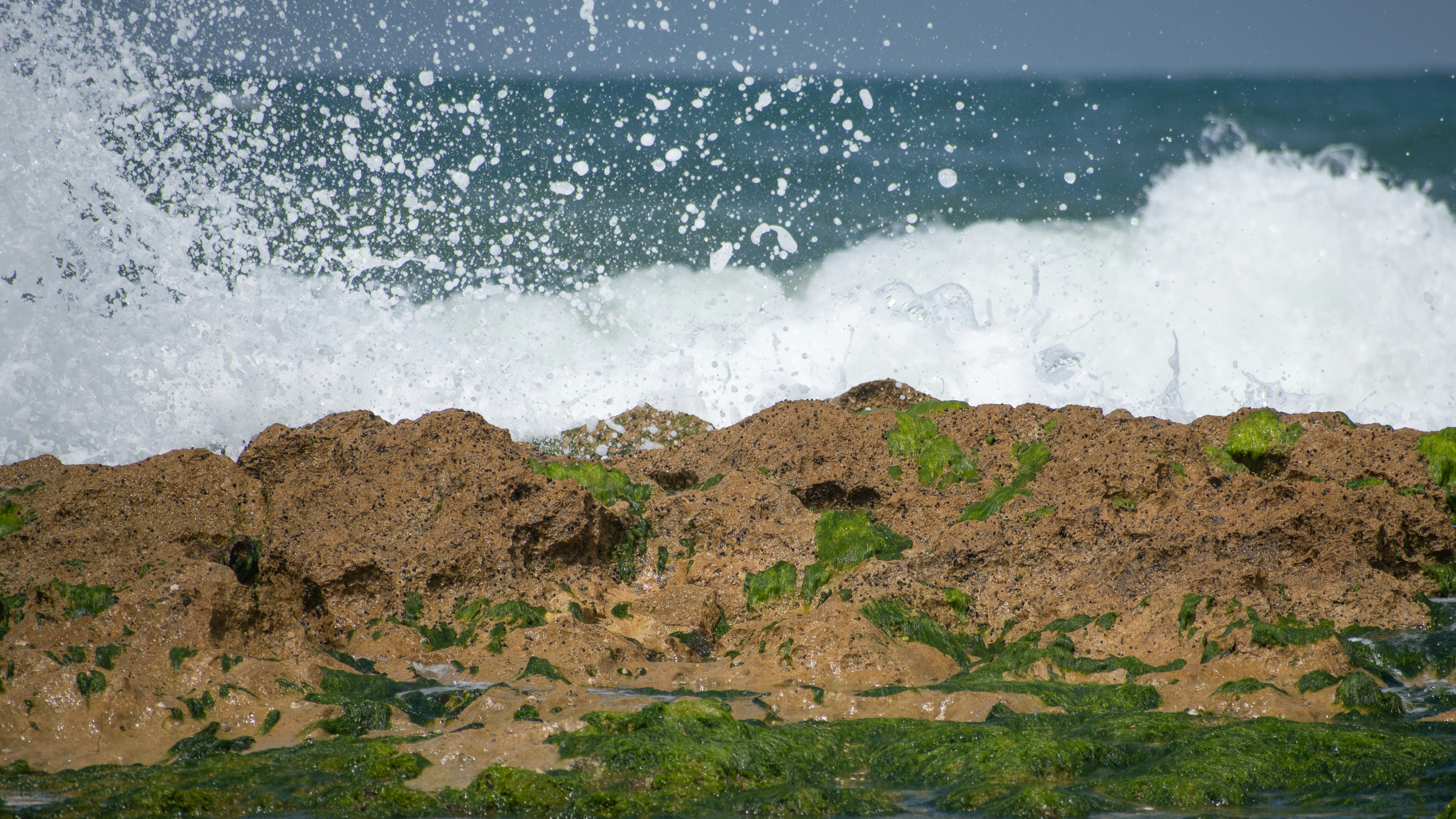 brown rocky mountain beside sea waves during daytime