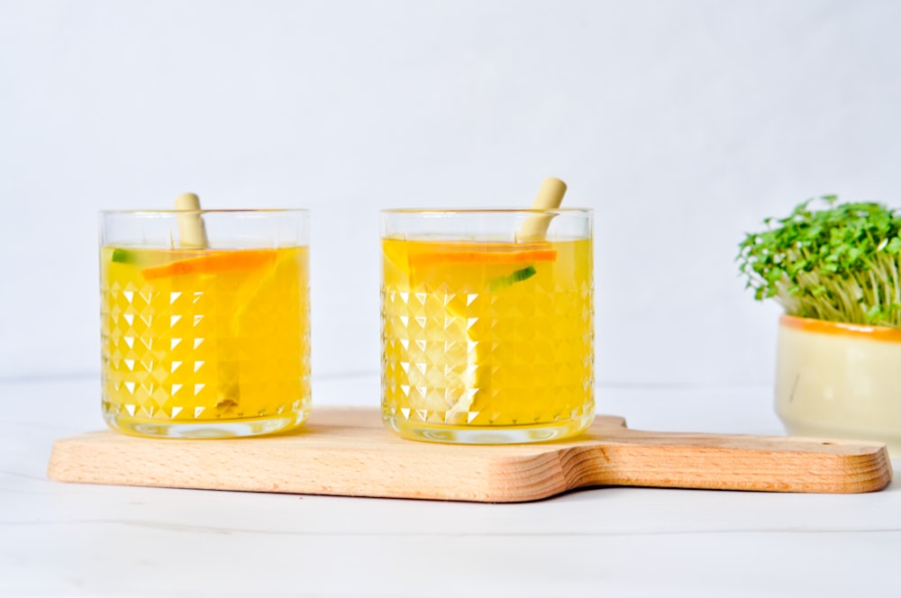 three clear drinking glasses with yellow liquid