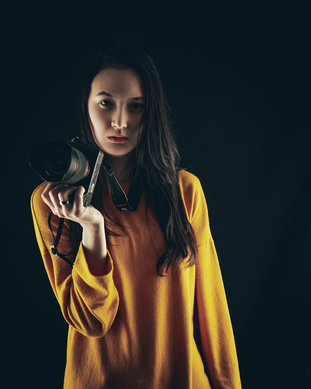 a woman in a yellow shirt holding a camera