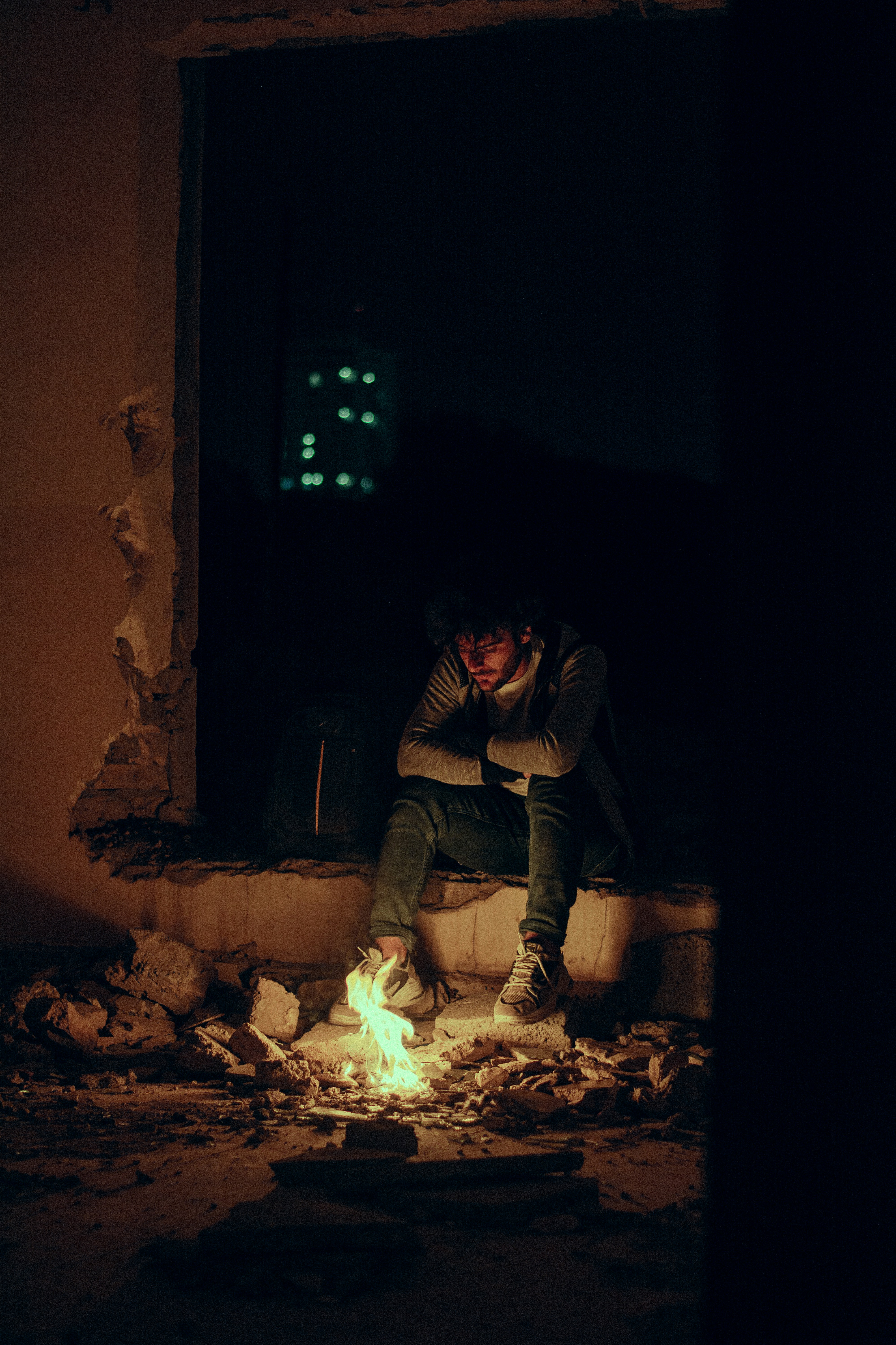 茶色のコンクリートレンガの上に座っている灰色のジャケットを着た男性