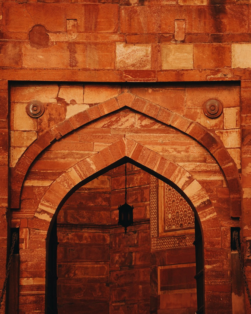 a brick archway with a clock on the side of it