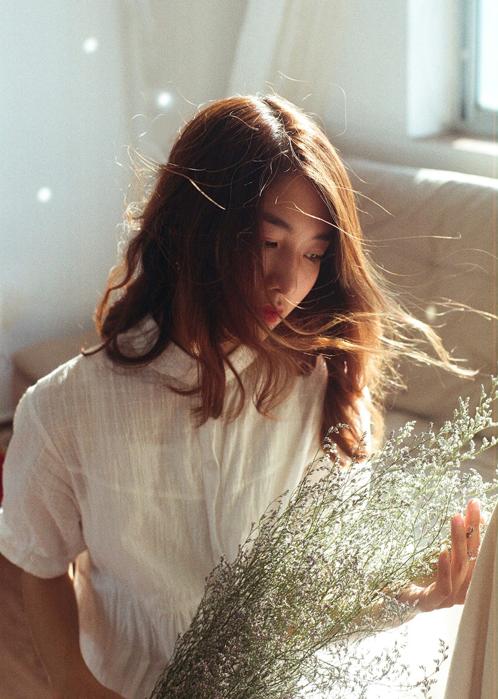 woman in white shirt holding green plant